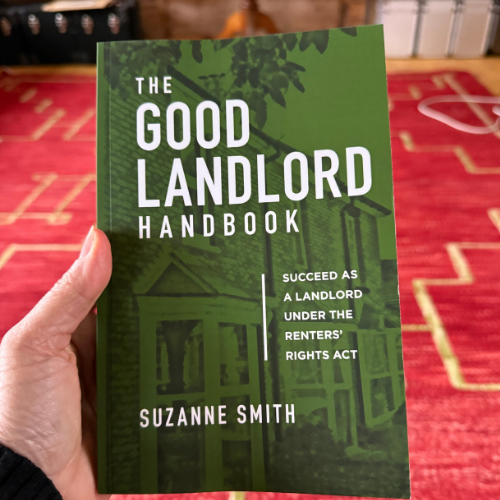 Book titled The Good Landlord Handbook held against the background of a red Moroccan rug